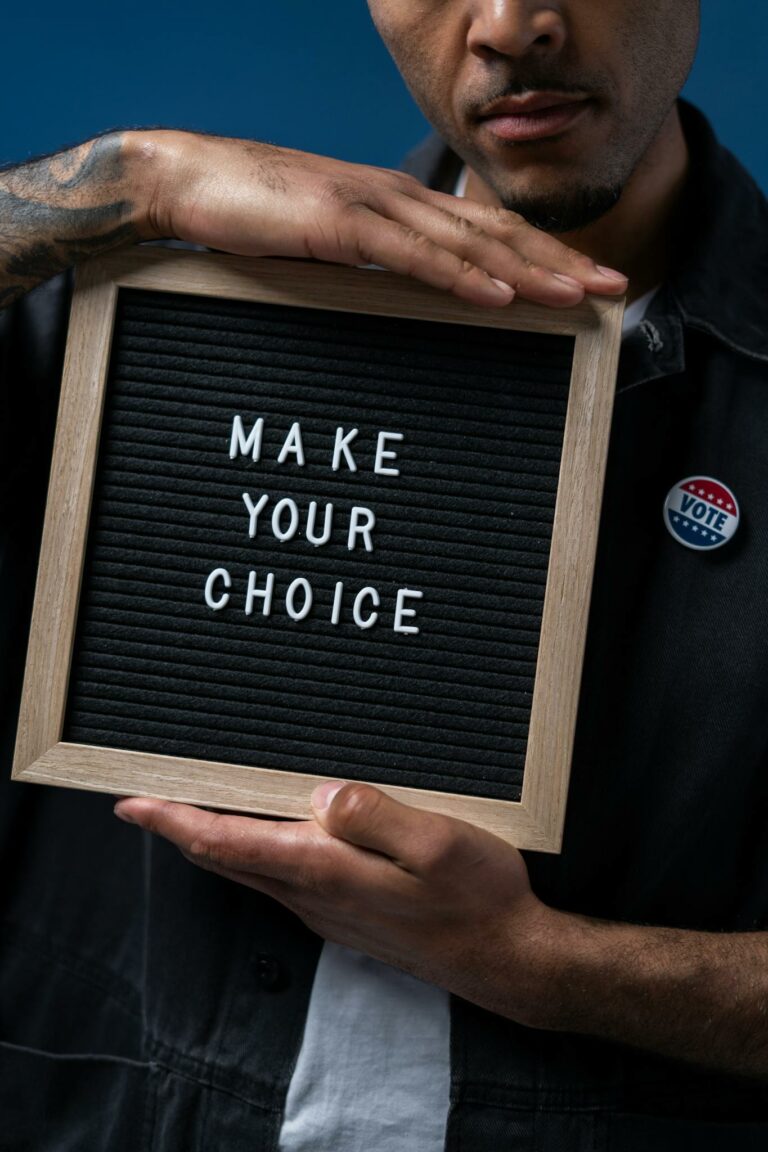 Close-up of a man holding a letter board with 'Make Your Choice' emphasizing voting importance.