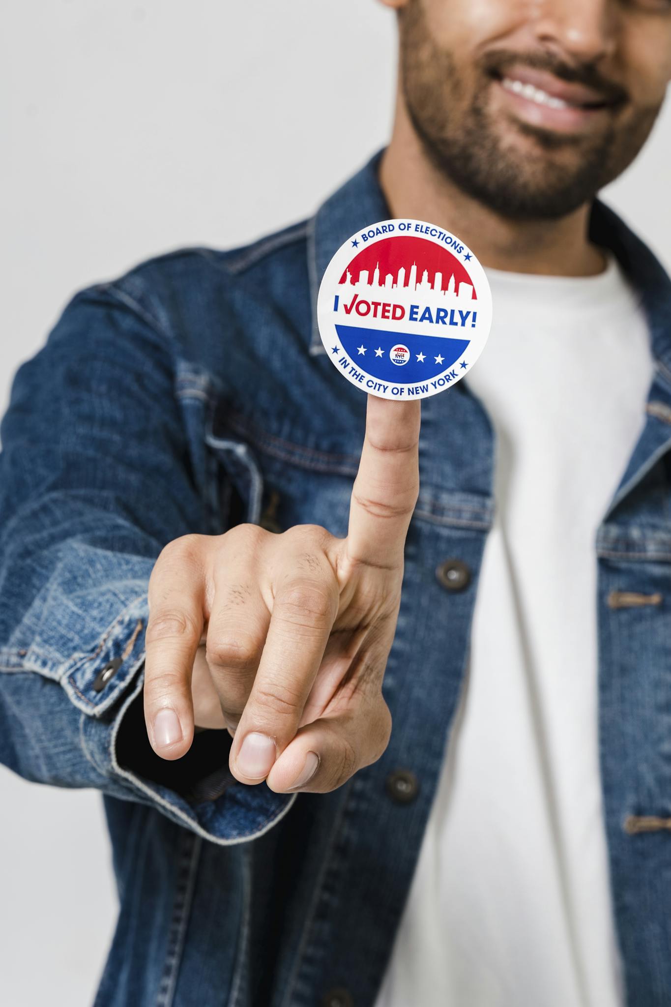 Close-up portrait of a smiling man showing an I Voted Early sticker on his finger, promoting civic engagement.